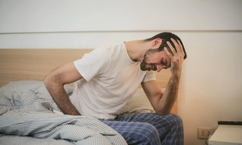 Man heeft een kater en zit op bed